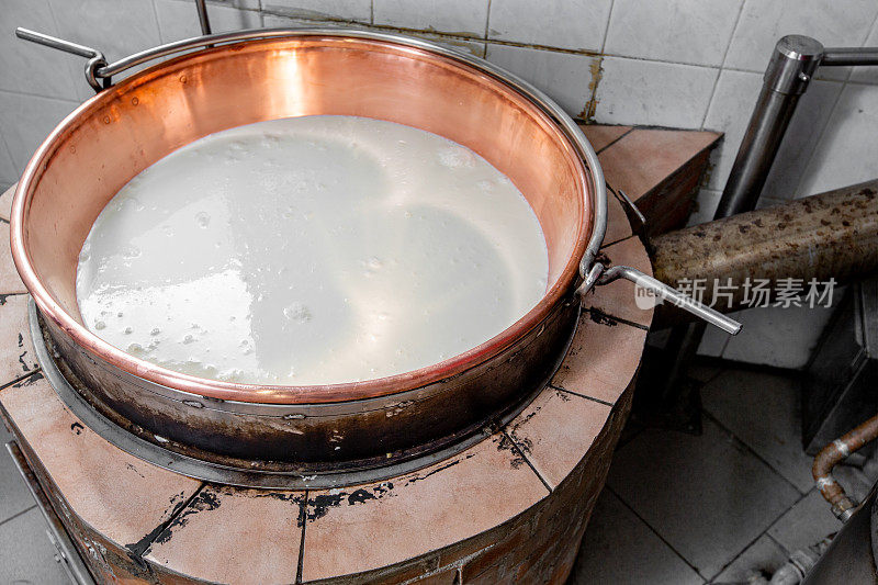 准备新鲜的山羊奶在旧炉子上做奶酪-高汤照片