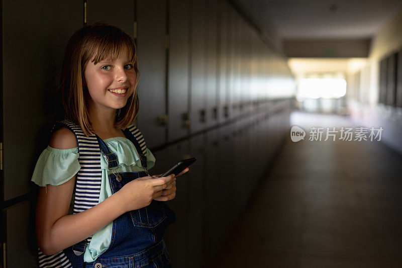 一名女生靠在走廊的储物柜上使用智能手机