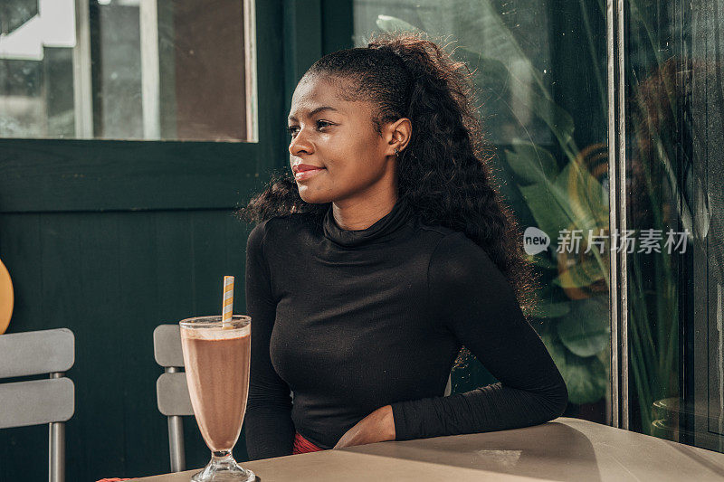 一个黑人女人独自坐在路边咖啡馆里