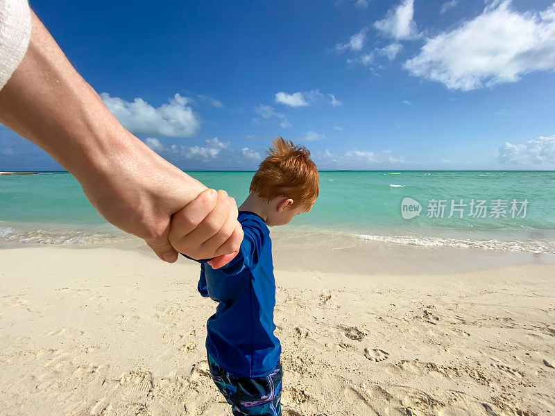 跟随我的概念-红发男孩牵着他母亲的手在加勒比热带海滩。