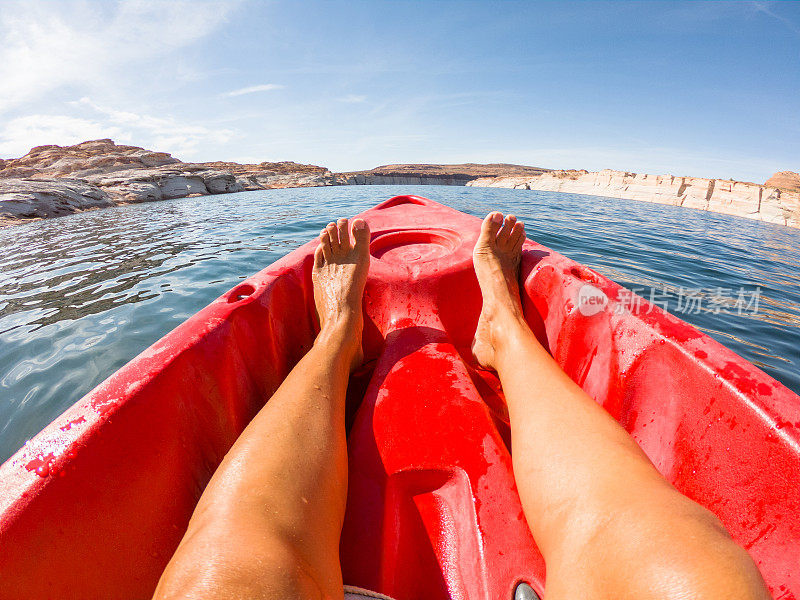 个人视角的年轻女子放松在红色的独木舟上漂浮在湖上