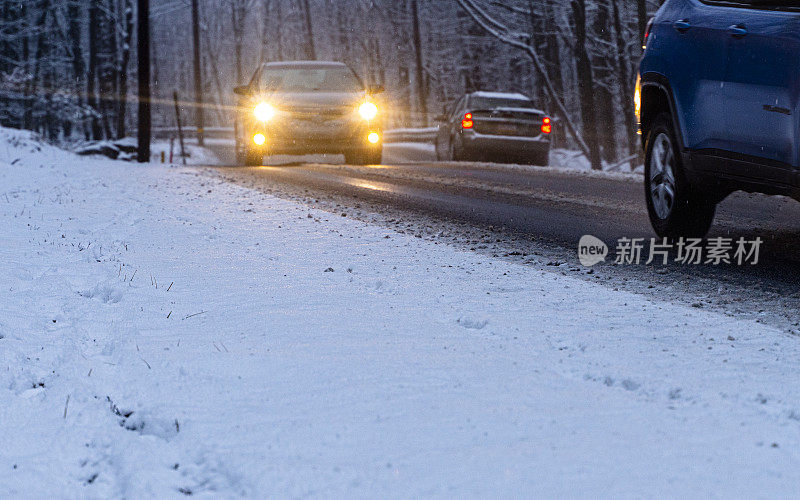 下着雪的汽车在一条小公路上行驶
