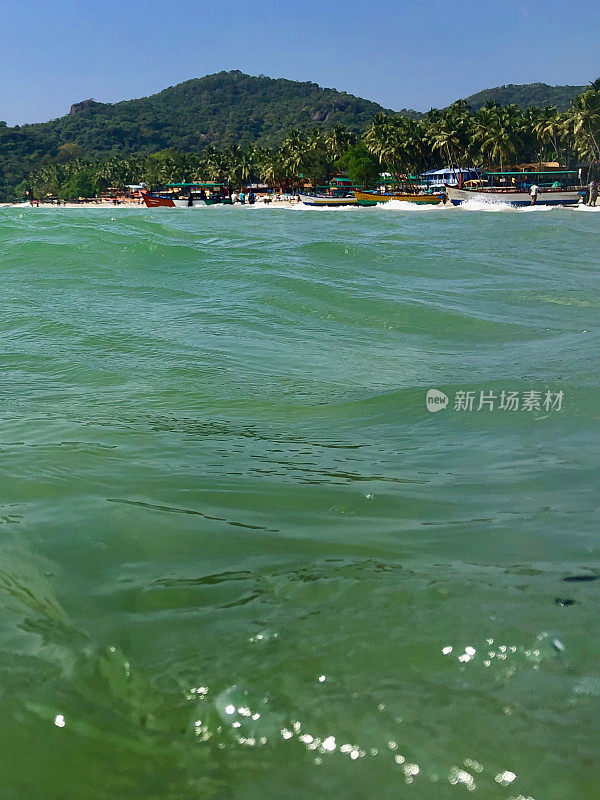 图片中的游船停泊在果阿海岸线上的海豚，海滩，蓝色的天空和蓝绿色的海，帕洛伦海滩，果阿，印度