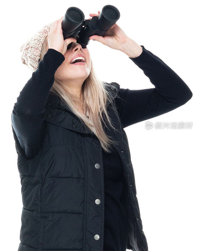 白种女性无袖站在白色背景前，头戴针织帽，手拿望远镜