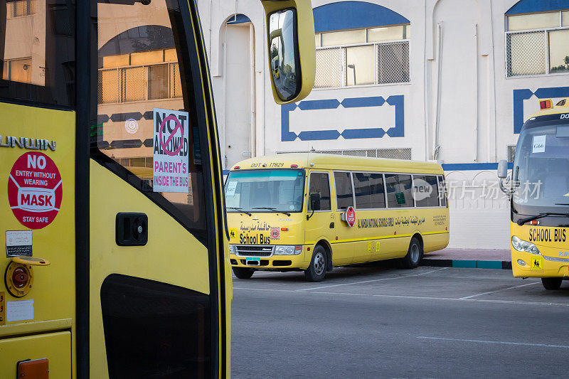 黄色校车在阿布扎比，阿拉伯联合酋长国，迪拜，阿联酋，海湾，中东。在校车上，意识标志和符号是用阿拉伯语写的。