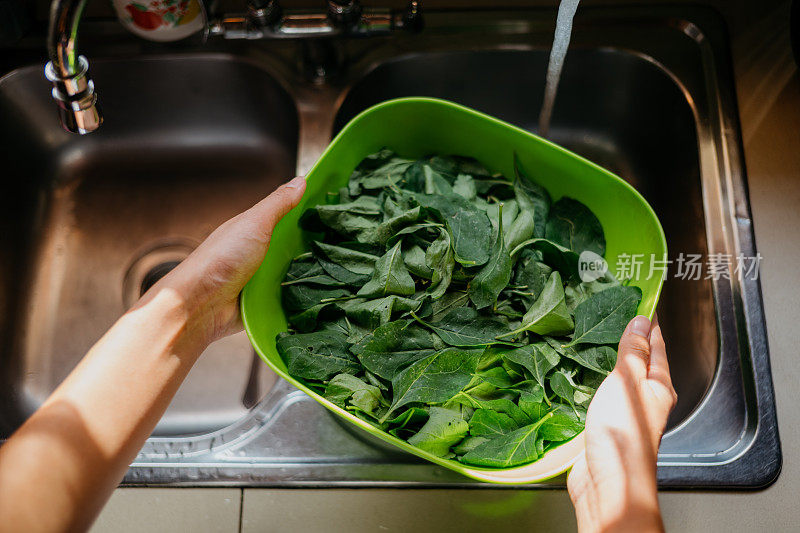 年轻女子在厨房水槽里洗蔬菜