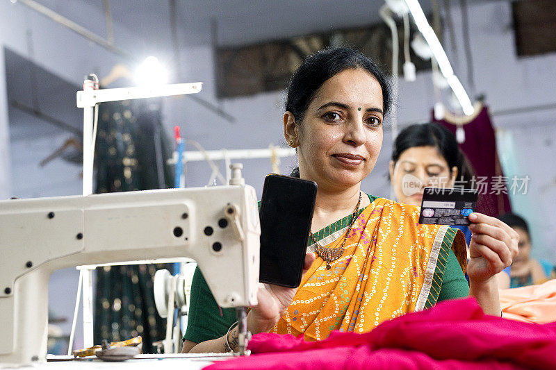 一名女工在纺织厂展示手机和信用卡
