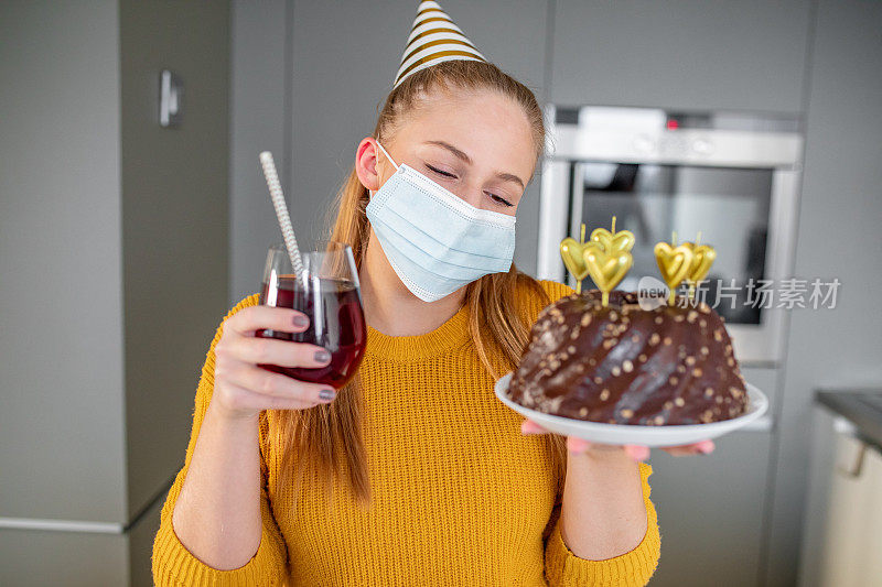 悲伤的年轻女子戴着面具独自在家庆祝生日