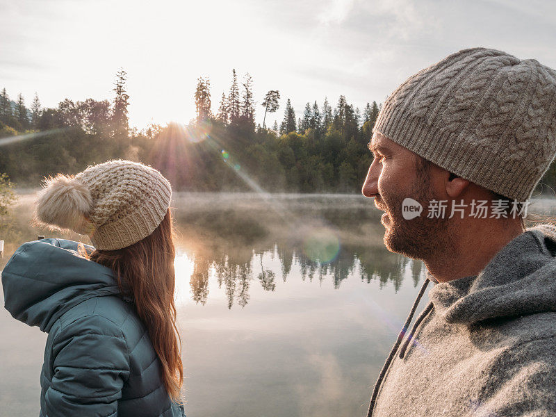 日出时分，一对情侣在湖边码头上休息