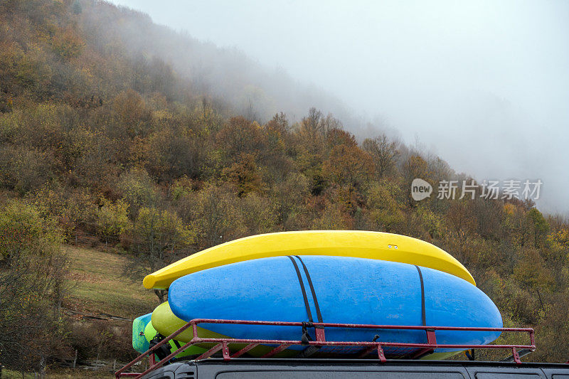车顶上的三块冲浪板朝向多雾的山脉背景。