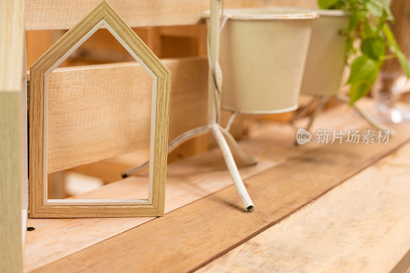 木桌上木质相框的特写和选择性聚焦拍摄，花瓶里插着植物，极简的北欧风格装饰。这是一种艺术构图，为家庭内部提供复制空间。
