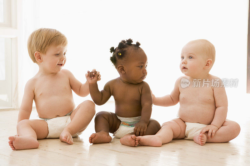 三个婴儿手牵着手坐在屋里
