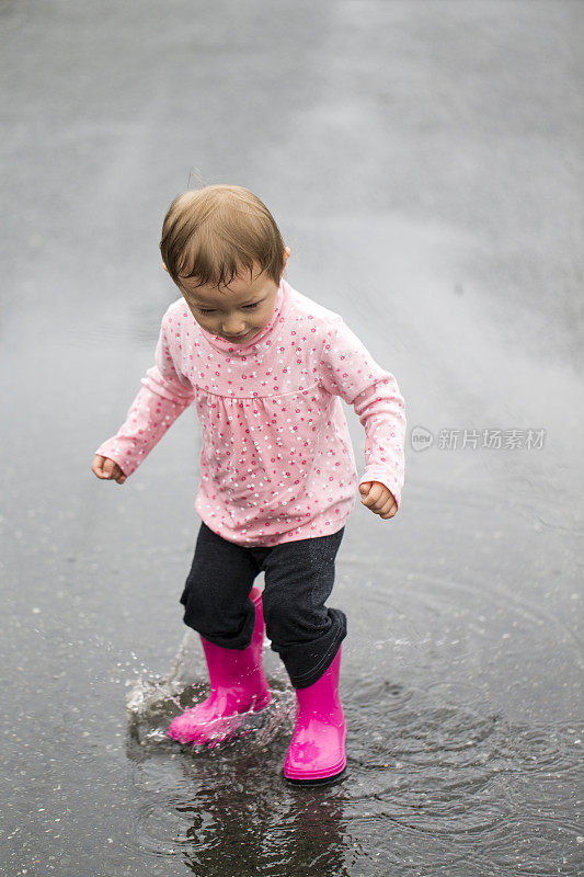 穿着雨靴在水坑里跳的小女孩