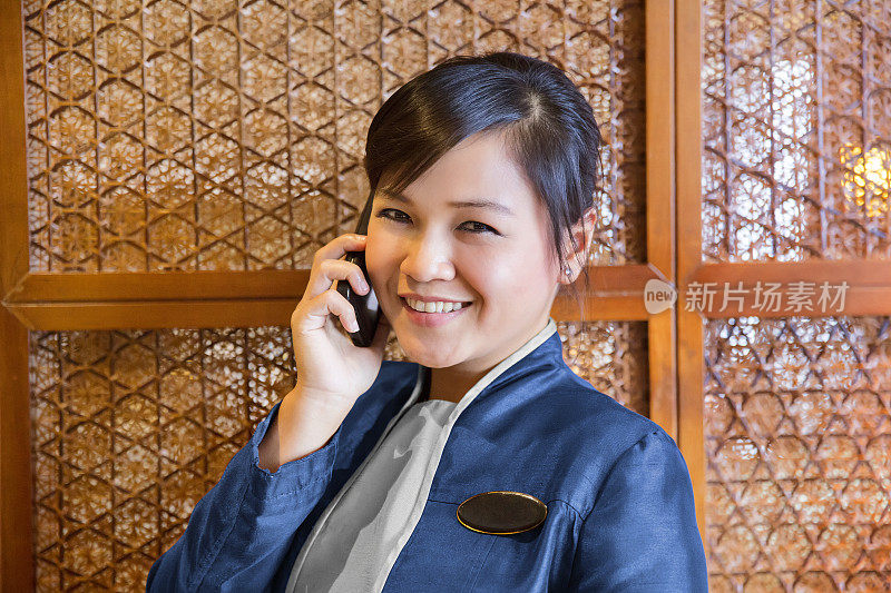 女亚洲酒店接待员在打电话和微笑
