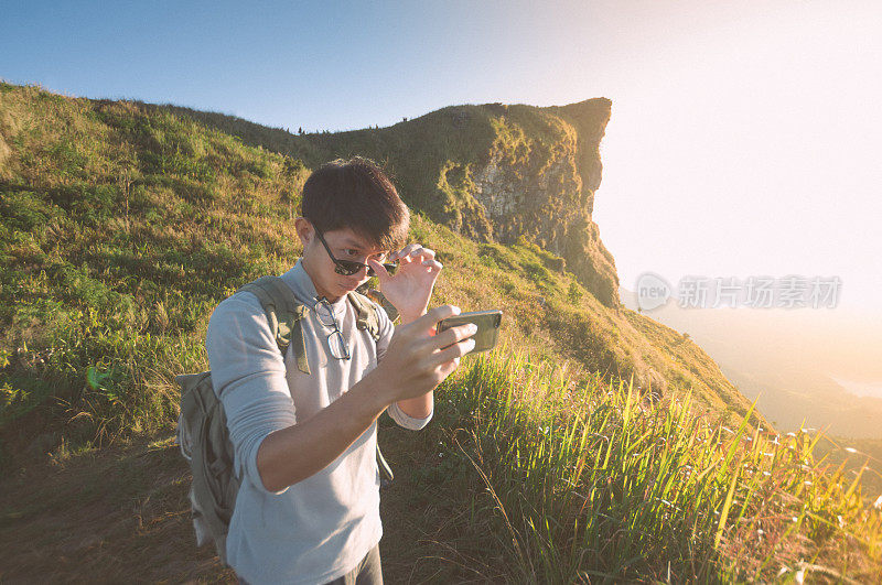 年轻的旅行者站在山上望着夕阳。