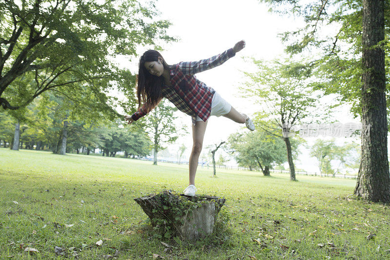 女孩骑在树干上。