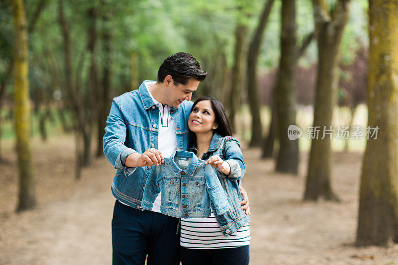 一对怀孕夫妇抱着婴儿外套