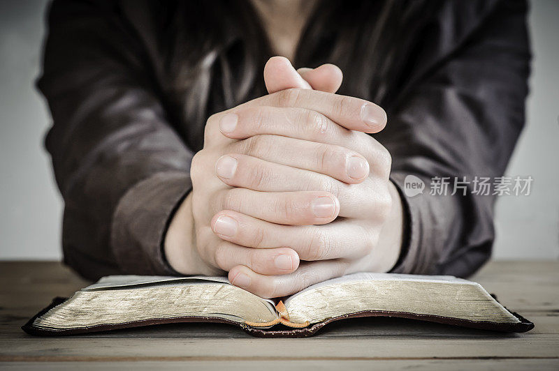 一个女人双手放在圣经上祈祷。