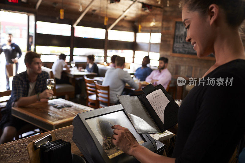 年轻女子在餐馆用触摸屏准备账单