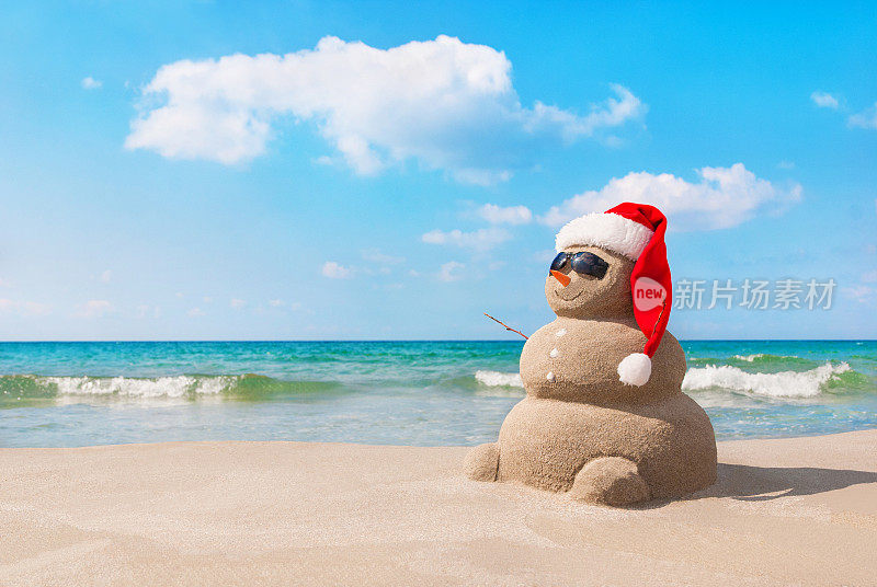 在沙滩上，戴着圣诞帽的圣诞雪人