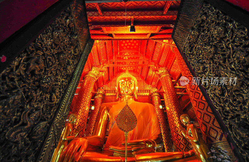 在寺庙里，金色的佛像雕刻在明亮的金色背景上