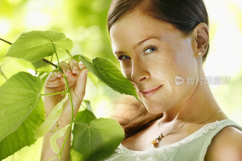 美丽的年轻女子享受着树叶的芳香