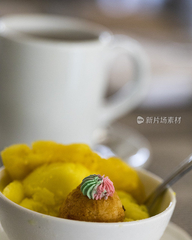 特写新鲜菠萝冰沙与一点甜椰子糕点和一杯咖啡。