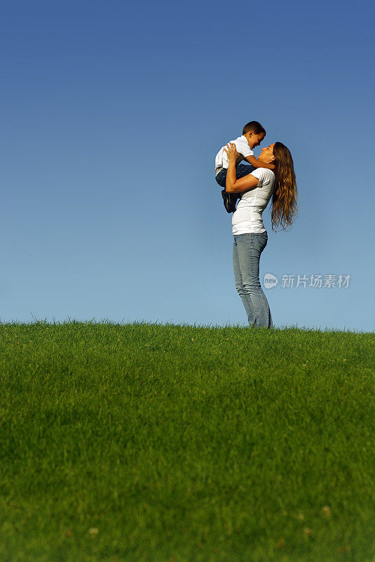 母亲抱着儿子在绿草山上