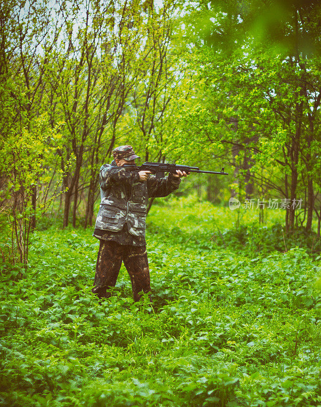 一名男子猎人瞄准从卡宾枪射击，狩猎在春天的森林在雨中，色调的照片