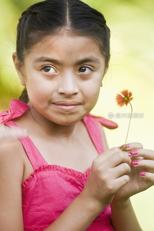 漂亮的西班牙孩子的脸穿着粉红色的裙子拿着花