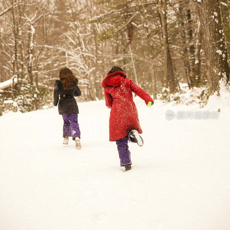 两个女孩，姐妹，在冬天的森林里玩雪