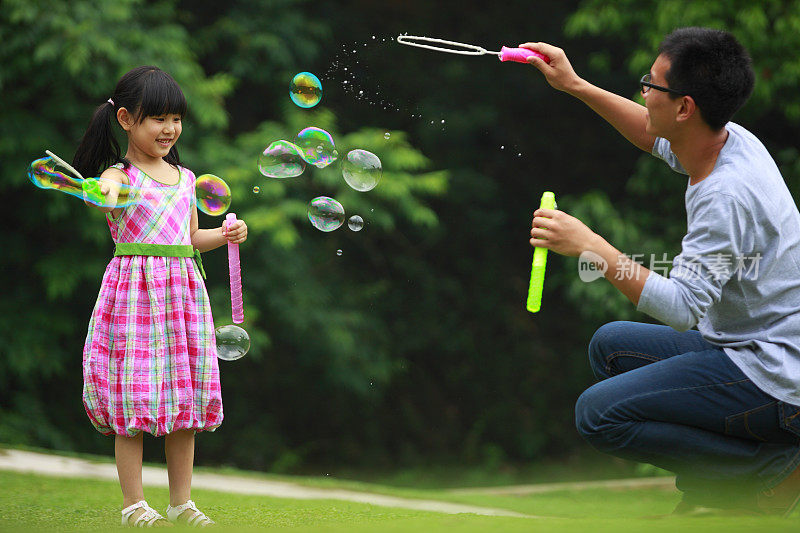 快乐的小女孩和她的父亲玩泡泡