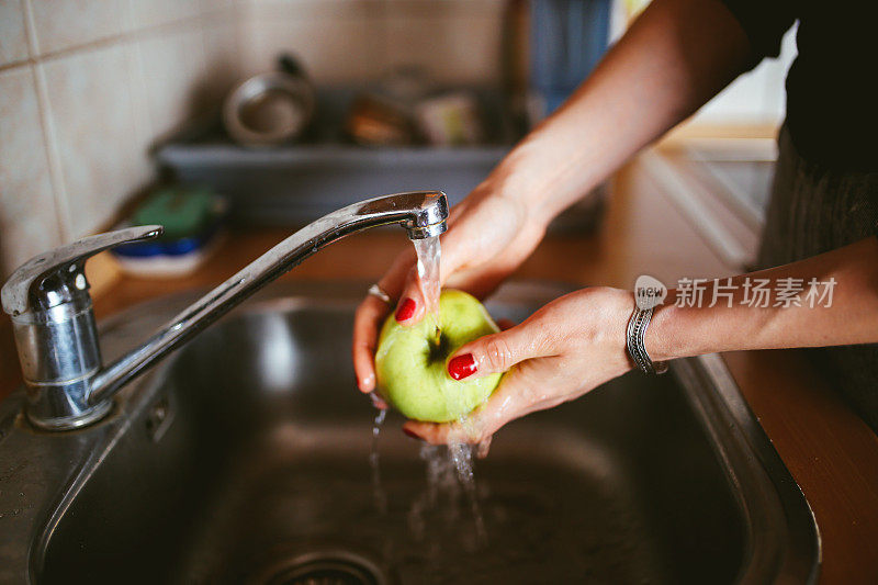 一个年轻女人在厨房里洗苹果
