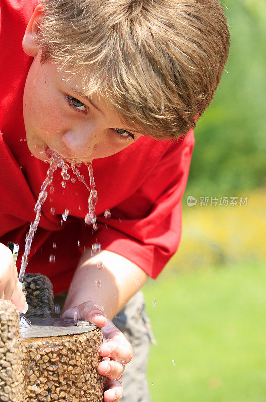 一个从喷泉里喝水的男生