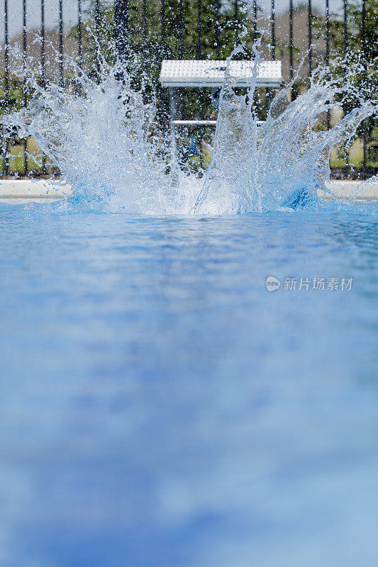游泳运动员从起跑处跳入蓝色泳池