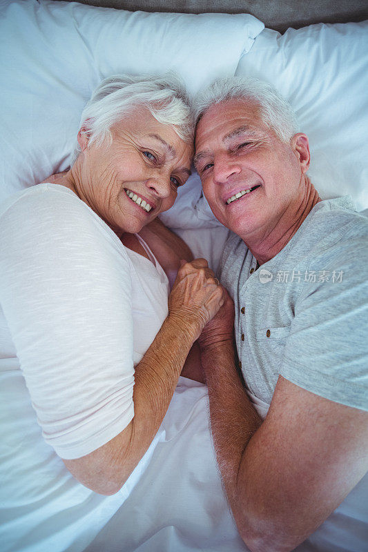 一对老年夫妇躺在床上手牵着手的肖像