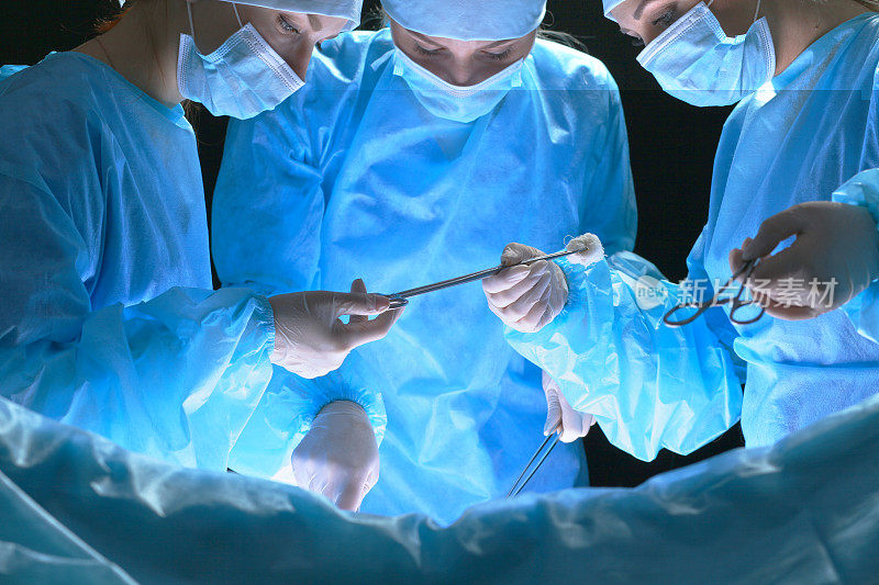 一组在手术室工作的外科医生，色调为蓝色