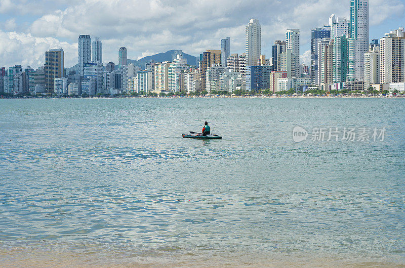 一名年轻人在巴西海滩上划着皮艇散步。