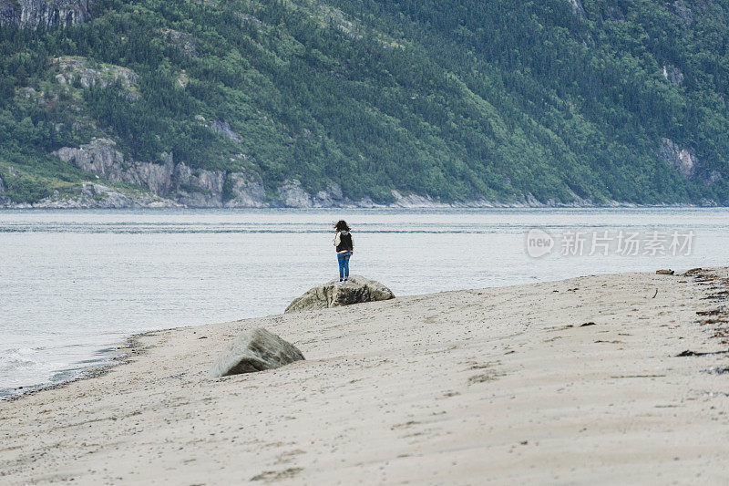 年轻的成年女子在海岸线上看着别处