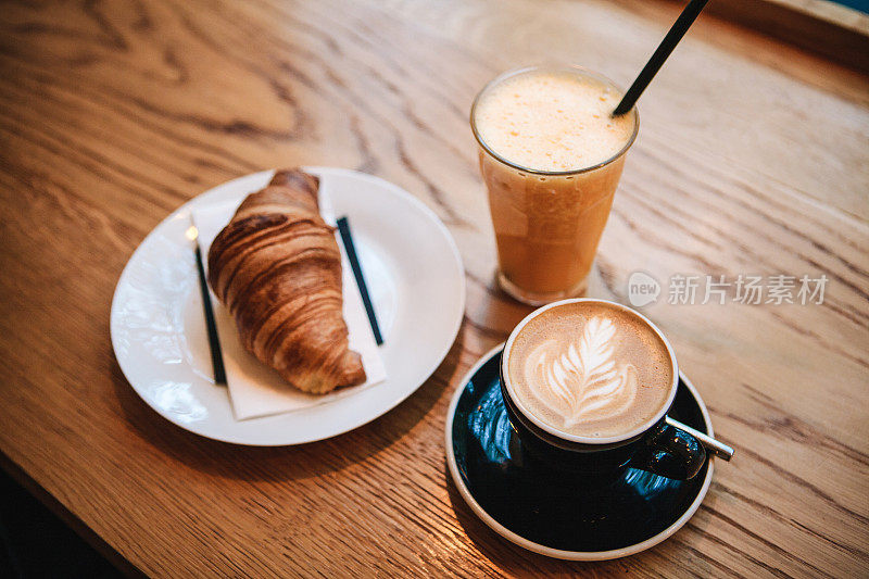 法式传统羊角面包甜点，在咖啡馆里的咖啡卡布奇诺和橙汁旁边作为早餐。