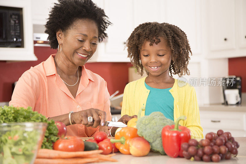祖母或母亲和女儿一起在家里厨房做饭。