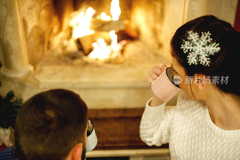 在圣诞节装饰的房子内部，一对恩爱的夫妇靠近壁炉
