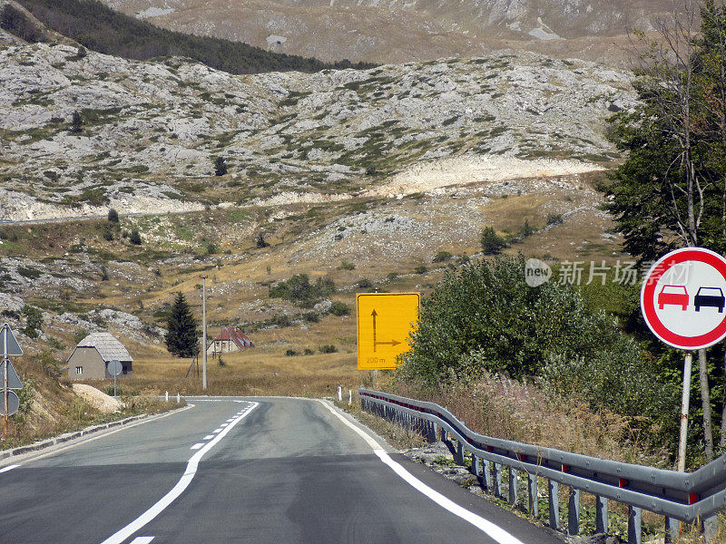 高速公路在山岳嶙峋的景观中设有禁止超车和方向路标