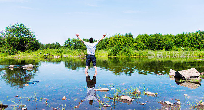 一个年轻人举着手臂站在湖里