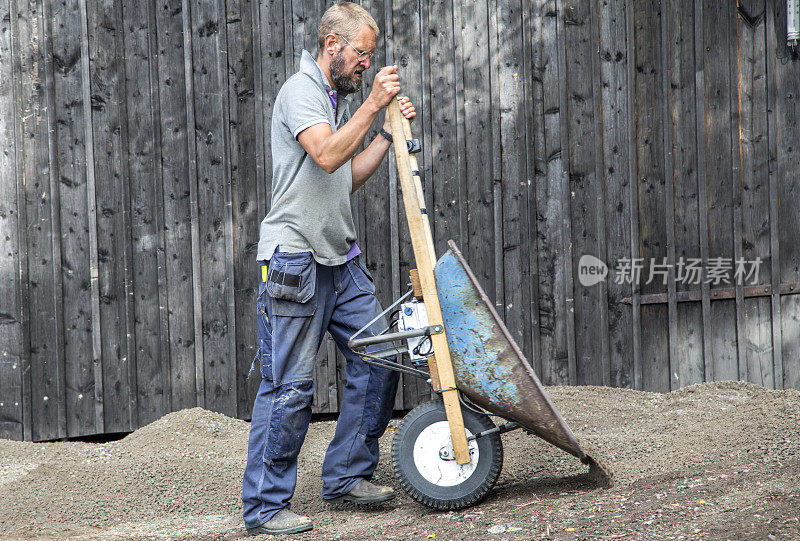 在瑞典斯德哥尔摩群岛，一名成年男子用手推车搬运砾石