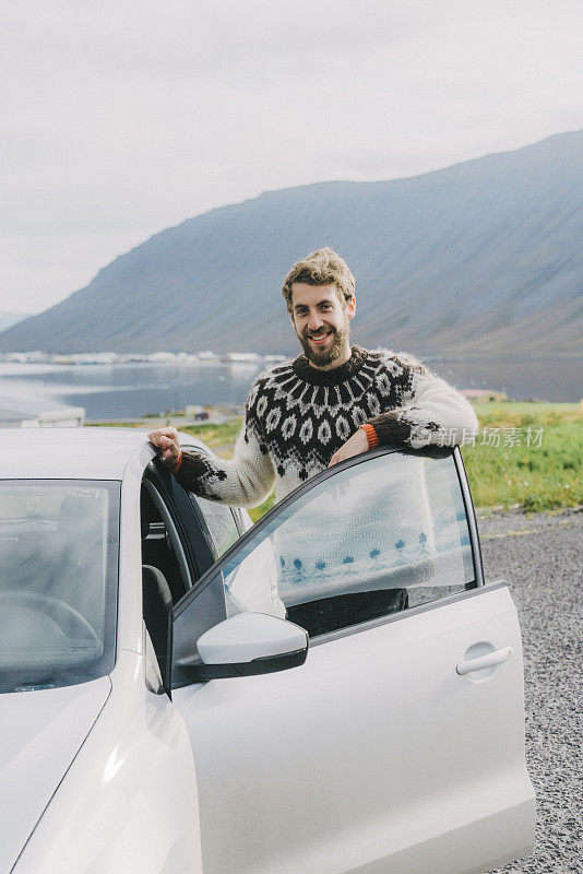 在冰岛，一个穿着冰岛毛衣的男人站在汽车旁边