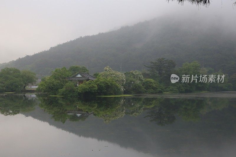 一个雾蒙蒙的早晨倒映在平静的湖面上