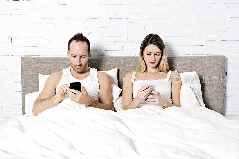 夫妻在床上玩手机