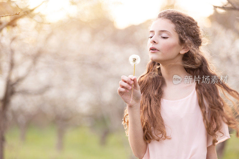 年轻美丽的女孩在春天被樱桃树包围