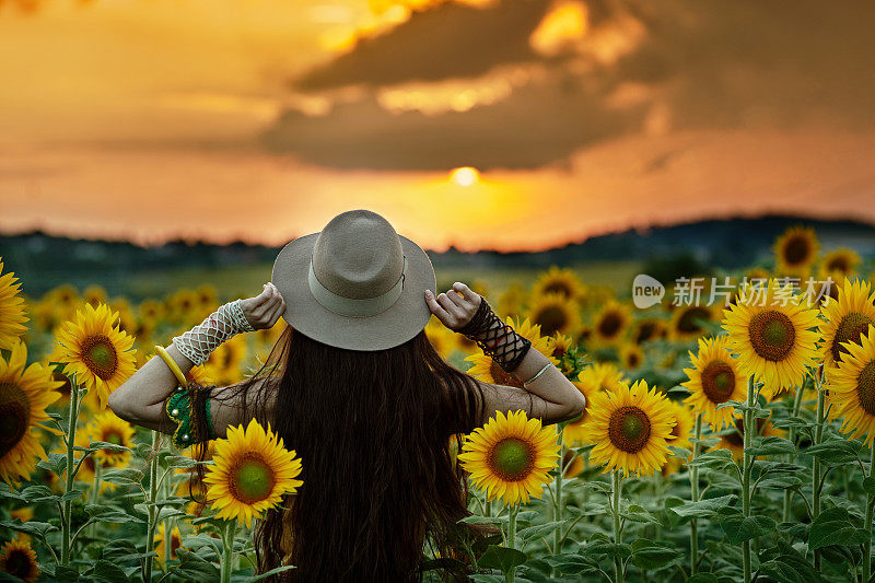 美丽的女人在向日葵地里享受自己